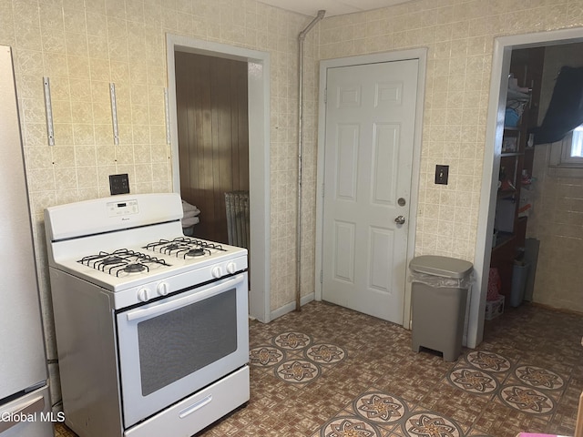 1341 7th Ave, Schenectady, NY 12303 - kitchen with white range with gas stovetop, tile walls, and tile patterned floors