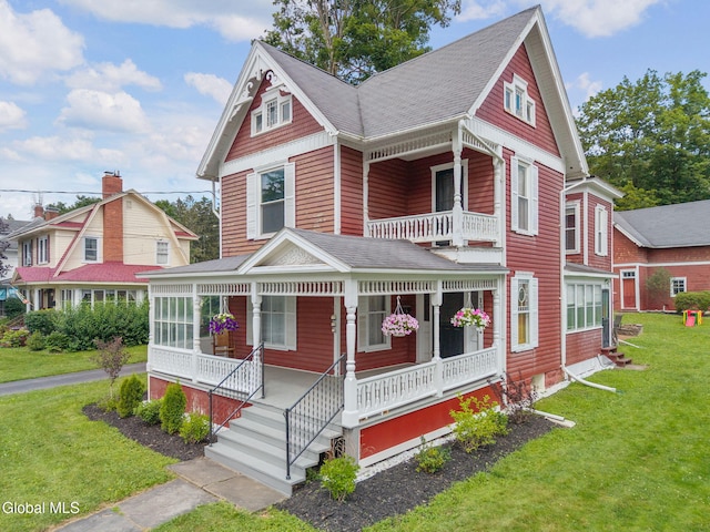 138 Elm St, Cobleskill, NY 12043 - victorian home featuring a balcony, covered porch, roof with shingles, and a front yard