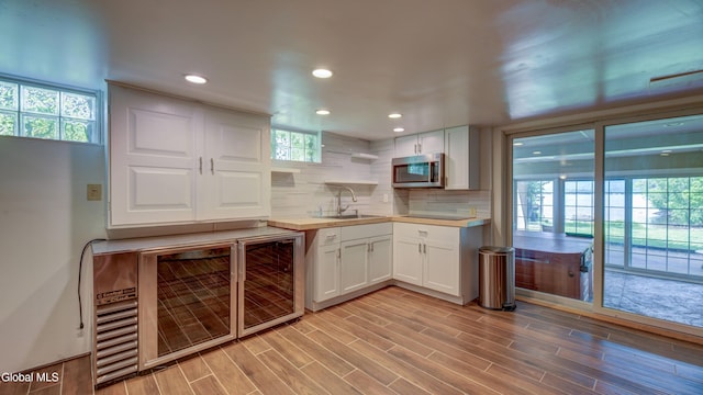 115 Shore Dr, Broadalbin, NY 12025 - kitchen featuring stainless steel microwave, light countertops, backsplash, white cabinetry, and light wood-type flooring