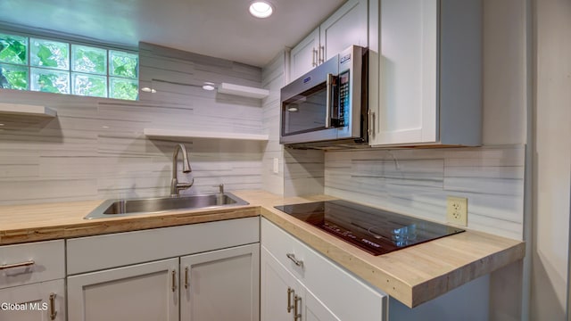 115 Shore Dr, Broadalbin, NY 12025 - kitchen with stainless steel microwave, black electric stovetop, butcher block counters, and backsplash