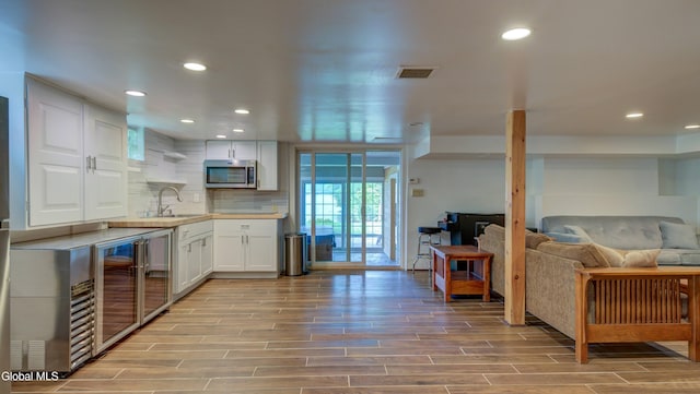 115 Shore Dr, Broadalbin, NY 12025 - kitchen with stainless steel microwave, white cabinets, light wood-style floors, wine cooler, and recessed lighting
