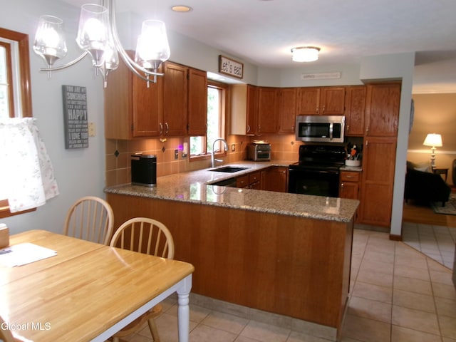 22 Frances Ln, Bethlehem, NY 12203 - kitchen featuring stainless steel microwave, black range with electric stovetop, brown cabinets, a peninsula, and backsplash