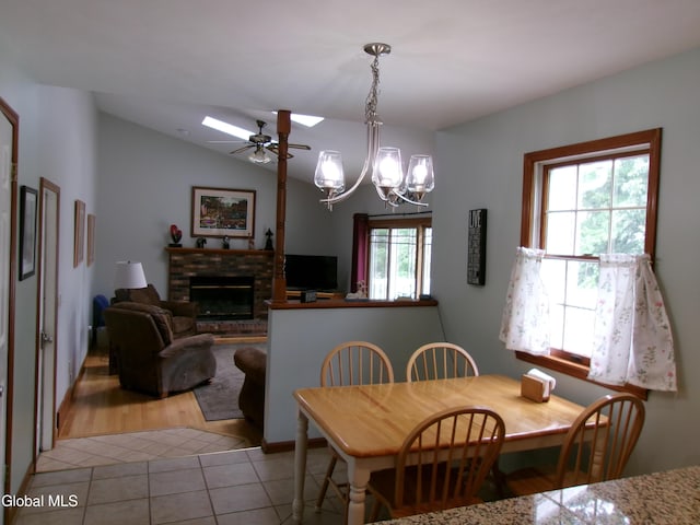 22 Frances Ln, Bethlehem, NY 12203 - dining area featuring light tile patterned flooring, a brick fireplace, a chandelier, a ceiling fan, and lofted ceiling