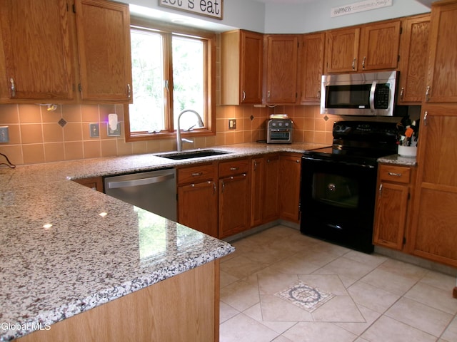 22 Frances Ln, Bethlehem, NY 12203 - kitchen with appliances with stainless steel finishes, decorative backsplash, brown cabinetry, light stone countertops, and light tile patterned flooring