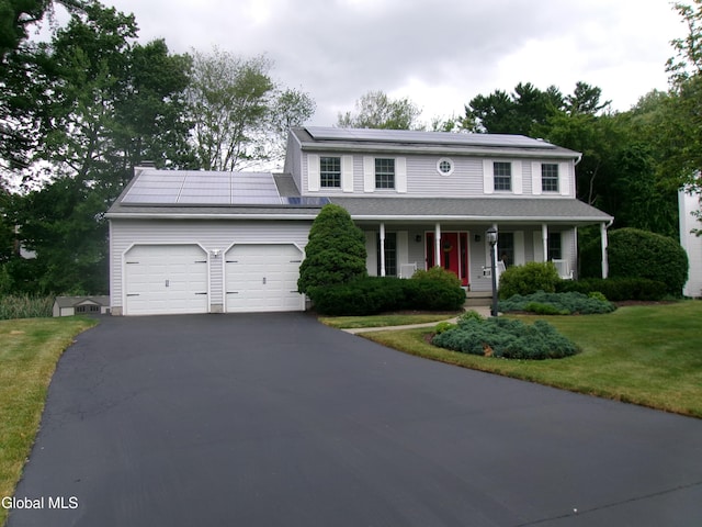 22 Frances Ln, Bethlehem, NY 12203 - view of front of home with covered porch, an attached garage, solar panels, asphalt driveway, and a front yard