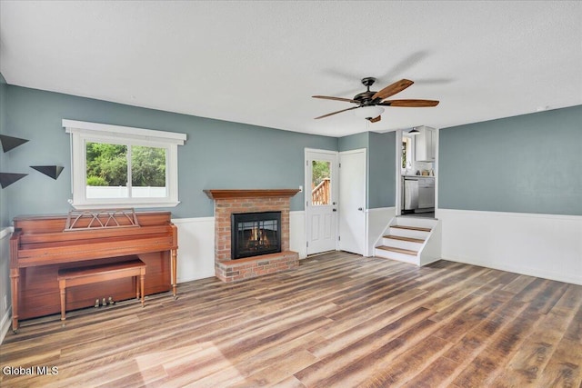 611 Via Ponderosa, Schenectady, NY 12303 - unfurnished living room with wood finished floors, ceiling fan, a brick fireplace, and a textured ceiling