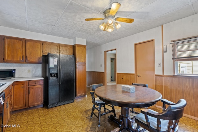 2780 Campbell Ave, Schenectady, NY 12306 - dining room featuring a wainscoted wall, a ceiling fan, light floors, and wooden walls