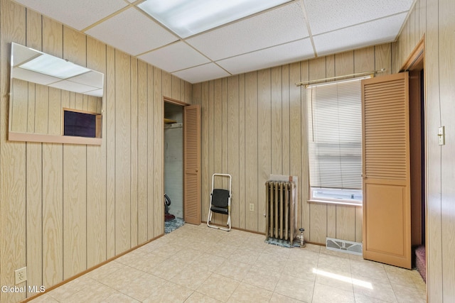 2780 Campbell Ave, Schenectady, NY 12306 - unfurnished room with radiator heating unit, a paneled ceiling, wood walls, and tile patterned floors