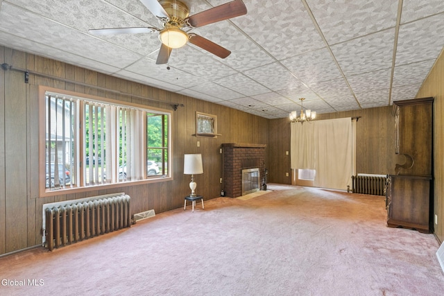 2780 Campbell Ave, Schenectady, NY 12306 - unfurnished living room featuring radiator, carpet floors, wood walls, a fireplace, and a chandelier