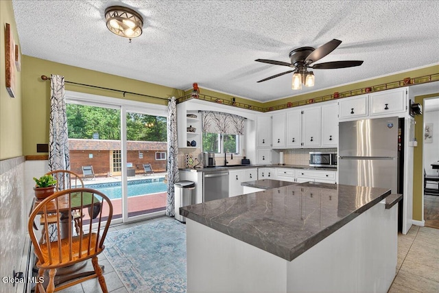 10 Heather Ln, Johnstown, NY 12078 - kitchen with stainless steel appliances, dark countertops, ceiling fan, light tile patterned flooring, and a textured ceiling