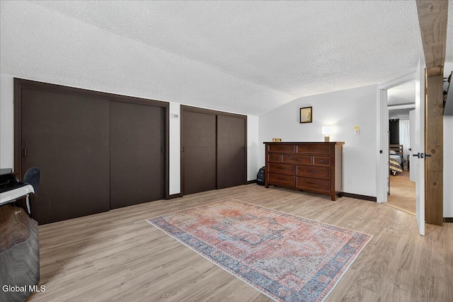 10 Heather Ln, Johnstown, NY 12078 - bedroom featuring two closets, light wood-style floors, a textured ceiling, and vaulted ceiling