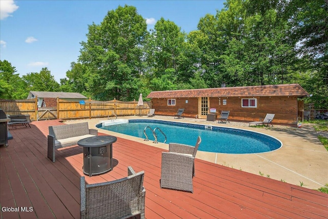 10 Heather Ln, Johnstown, NY 12078 - view of swimming pool featuring a deck, a fenced backyard, an outdoor fire pit, and view of wooded area