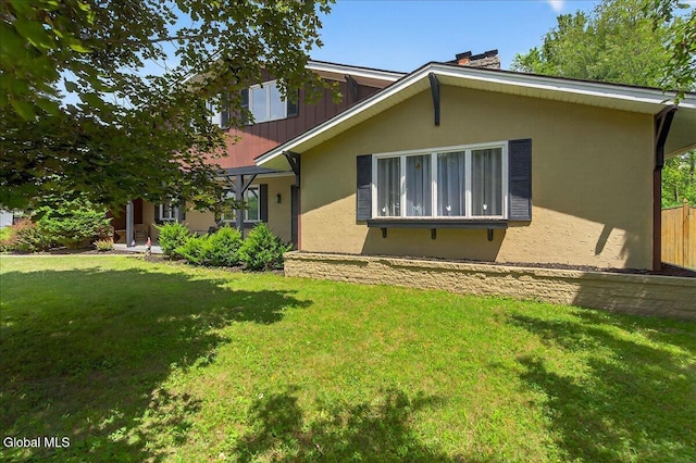 10 Heather Ln, Johnstown, NY 12078 - view of front of house with a front yard, stucco siding, and a chimney