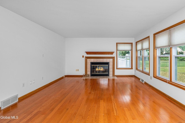 3002 Morgan Ct, Schenectady, NY 12306 - unfurnished living room featuring light wood finished floors, healthy amount of natural light, and a tile fireplace