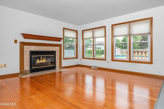 3002 Morgan Ct, Schenectady, NY 12306 - unfurnished living room featuring a tiled fireplace, plenty of natural light, and wood finished floors