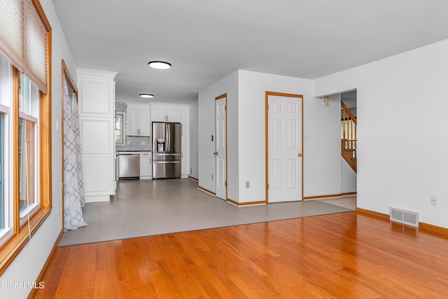 3002 Morgan Ct, Schenectady, NY 12306 - unfurnished living room with light wood finished floors, healthy amount of natural light, and stairway