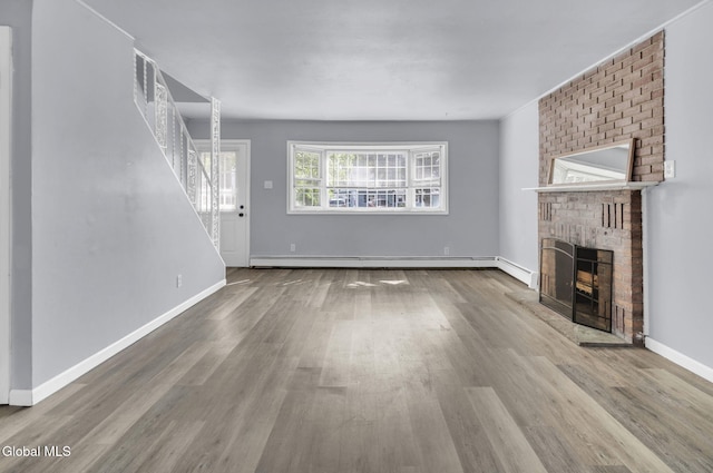 6 Briarwood Rd, Colonie, NY 12211 - unfurnished living room featuring a brick fireplace, wood finished floors, baseboard heating, and stairs