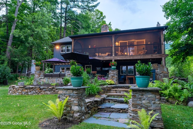 83 Pilot Knob Rd, Queensbury, NY 12804 - rear view of property featuring a chimney, a sunroom, stone siding, a patio, and a yard