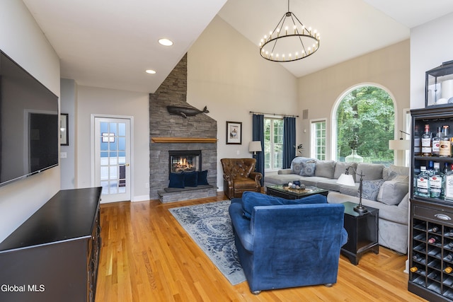 222 Bell Ct, Guilderland, NY 12303 - living room featuring a stone fireplace, a chandelier, high vaulted ceiling, and wood finished floors