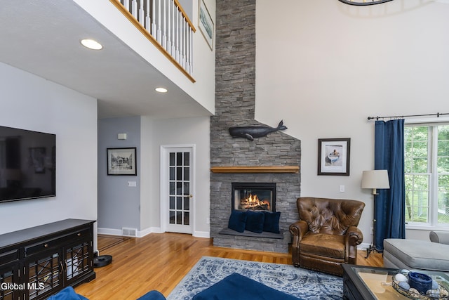 222 Bell Ct, Guilderland, NY 12303 - living room with a high ceiling, wood finished floors, a stone fireplace, and recessed lighting
