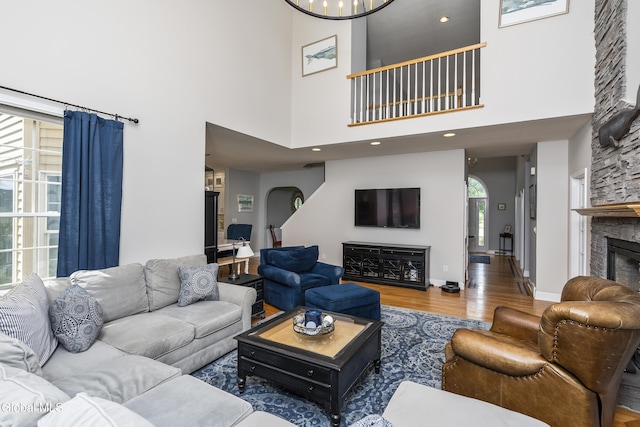 222 Bell Ct, Guilderland, NY 12303 - living room featuring a fireplace, wood finished floors, a towering ceiling, and arched walkways