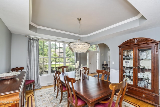 222 Bell Ct, Guilderland, NY 12303 - dining room featuring a raised ceiling, a chandelier, arched walkways, light wood-style flooring, and crown molding