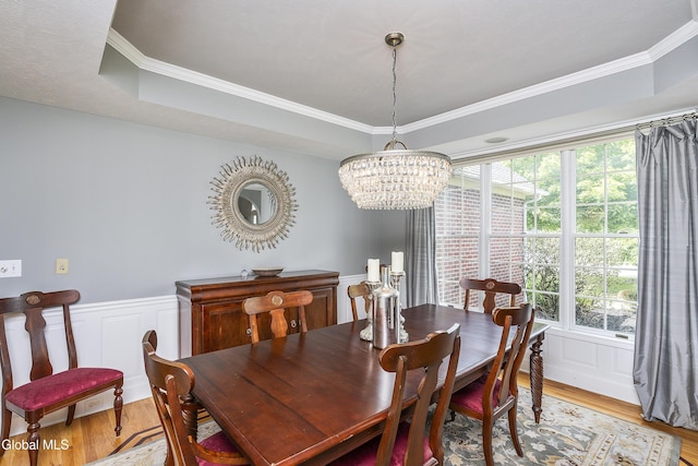222 Bell Ct, Guilderland, NY 12303 - dining room featuring a chandelier, light wood finished floors, crown molding, wainscoting, and a decorative wall