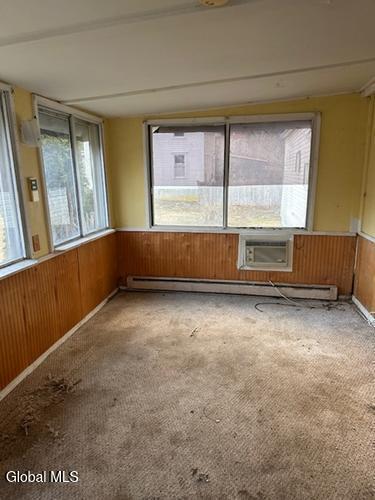 873 W Fulton Rd, Fulton, NY 12187 - unfurnished room featuring carpet floors, wood walls, wainscoting, and an AC wall unit