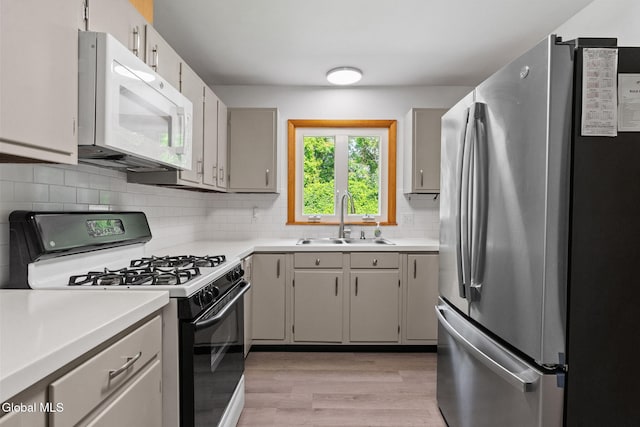 2351 Oakland Ave, Schenectady, NY 12309 - kitchen featuring freestanding refrigerator, white microwave, black gas stove, light wood-style flooring, and light countertops