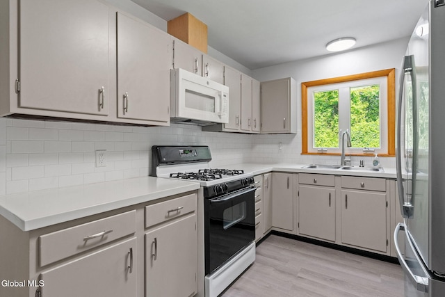 2351 Oakland Ave, Schenectady, NY 12309 - kitchen with white microwave, stainless steel fridge, black range with gas stovetop, light wood-type flooring, and decorative backsplash