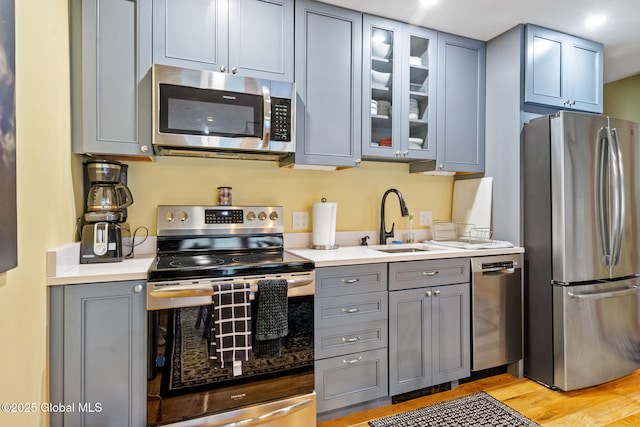 35 Scribner Hollow Rd # E3, Hunter, NY 12442 - kitchen with appliances with stainless steel finishes, gray cabinetry, light countertops, light wood finished floors, and glass insert cabinets