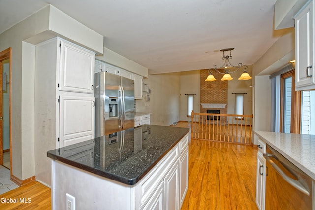 33 Cindy Ln, Halfmoon, NY 12065 - kitchen with appliances with stainless steel finishes, light wood-style flooring, white cabinets, dark stone counters, and decorative light fixtures