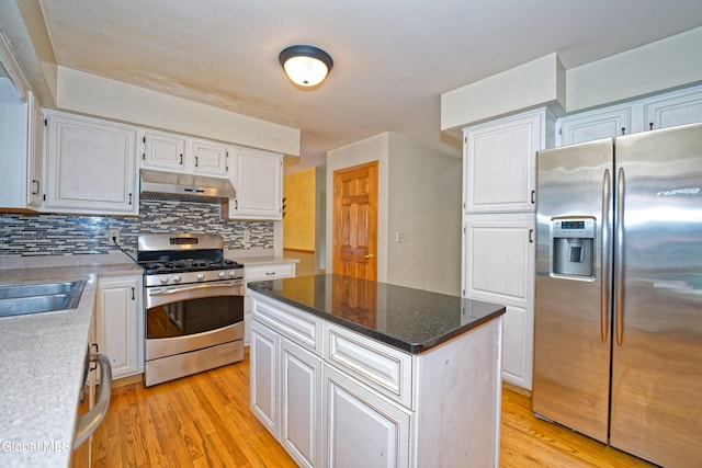 33 Cindy Ln, Halfmoon, NY 12065 - kitchen featuring appliances with stainless steel finishes, under cabinet range hood, light wood-style flooring, tasteful backsplash, and white cabinets