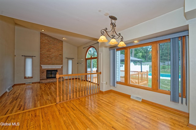 33 Cindy Ln, Halfmoon, NY 12065 - unfurnished living room with wood finished floors, vaulted ceiling, a brick fireplace, and a chandelier