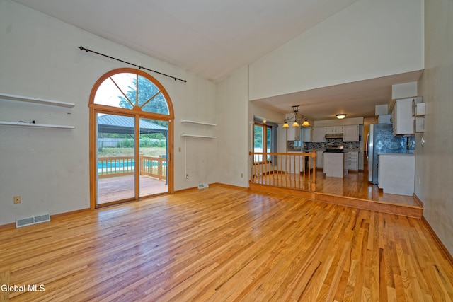 33 Cindy Ln, Halfmoon, NY 12065 - unfurnished living room with high vaulted ceiling, light wood finished floors, a chandelier, and healthy amount of natural light