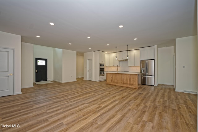 145C Bozenkill Rd, Altamont, NY 12009 - kitchen with stainless steel appliances, open floor plan, white cabinetry, light wood finished floors, and light countertops