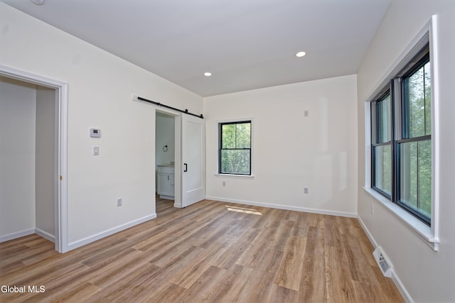 145C Bozenkill Rd, Altamont, NY 12009 - unfurnished bedroom featuring a barn door, light wood finished floors, recessed lighting, and ensuite bath