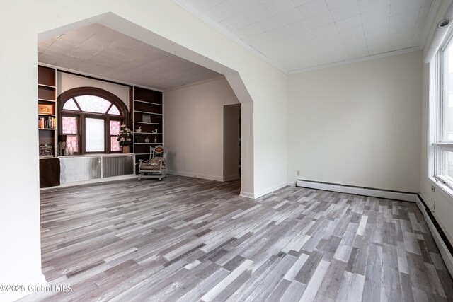 128 Circular St, Saratoga Springs, NY 12866 - spare room with crown molding, built in shelves, arched walkways, wood finished floors, and plenty of natural light