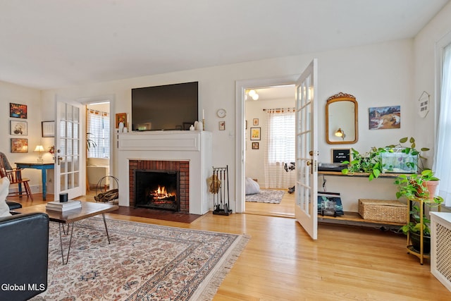 1556 Wendell Ave, Schenectady, NY 12308 - living area with french doors, light wood-style floors, a brick fireplace, and radiator