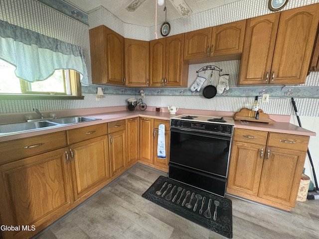 5 Spring St, Port Henry, NY 12974 - kitchen with electric stove, wallpapered walls, brown cabinets, light wood-type flooring, and light countertops