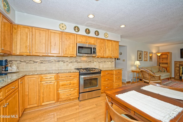35 Warwick Way, Niskayuna, NY 12309 - kitchen with appliances with stainless steel finishes, light wood finished floors, a textured ceiling, backsplash, and open floor plan