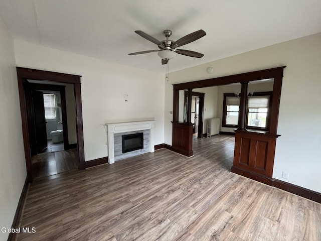 1822 7th St, Rensselaer, NY 12144 - unfurnished living room with wood finished floors, a glass covered fireplace, a ceiling fan, and radiator