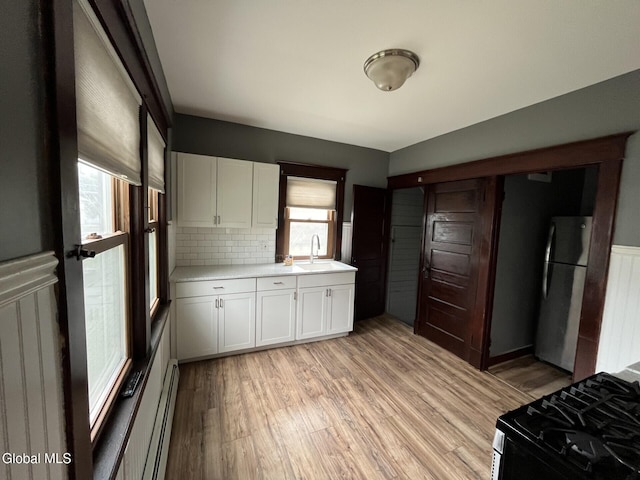 1822 7th St, Rensselaer, NY 12144 - kitchen featuring freestanding refrigerator, gas stove, a baseboard heating unit, white cabinetry, and light countertops