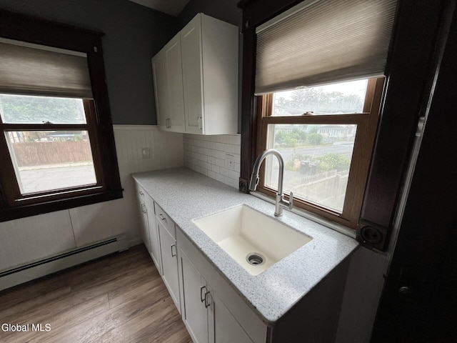 1822 7th St, Rensselaer, NY 12144 - kitchen featuring a baseboard radiator, white cabinets, light wood-style flooring, and a wainscoted wall