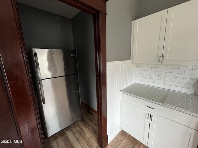 1822 7th St, Rensselaer, NY 12144 - kitchen with freestanding refrigerator, light wood-style flooring, light stone counters, wainscoting, and white cabinetry