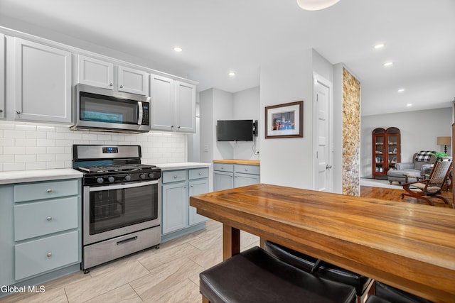 55 Crescent Ave, Saratoga Springs, NY 12866 - kitchen featuring appliances with stainless steel finishes, tasteful backsplash, recessed lighting, white cabinetry, and butcher block counters