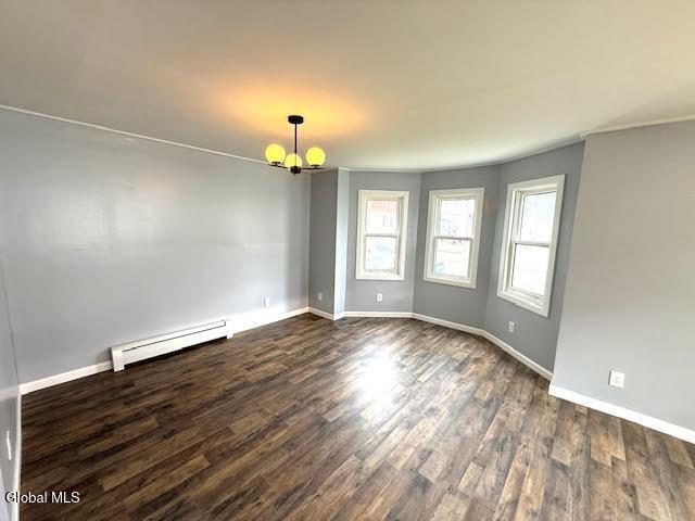 1338 Crane St, Schenectady, NY 12303 - empty room with dark wood finished floors, a baseboard radiator, and a chandelier
