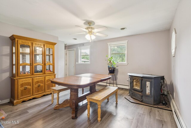 420 Caverns Rd, Cobleskill, NY 12092 - dining area featuring a baseboard heating unit, a wood stove, light wood-style floors, and a ceiling fan