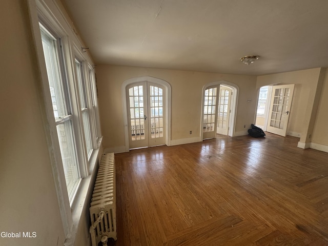 261 Altamont Ave, Schenectady, NY 12304 - spare room with french doors, radiator heating unit, arched walkways, and wood finished floors