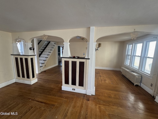 261 Altamont Ave, Schenectady, NY 12304 - unfurnished living room with arched walkways, radiator heating unit, stairway, and a chandelier